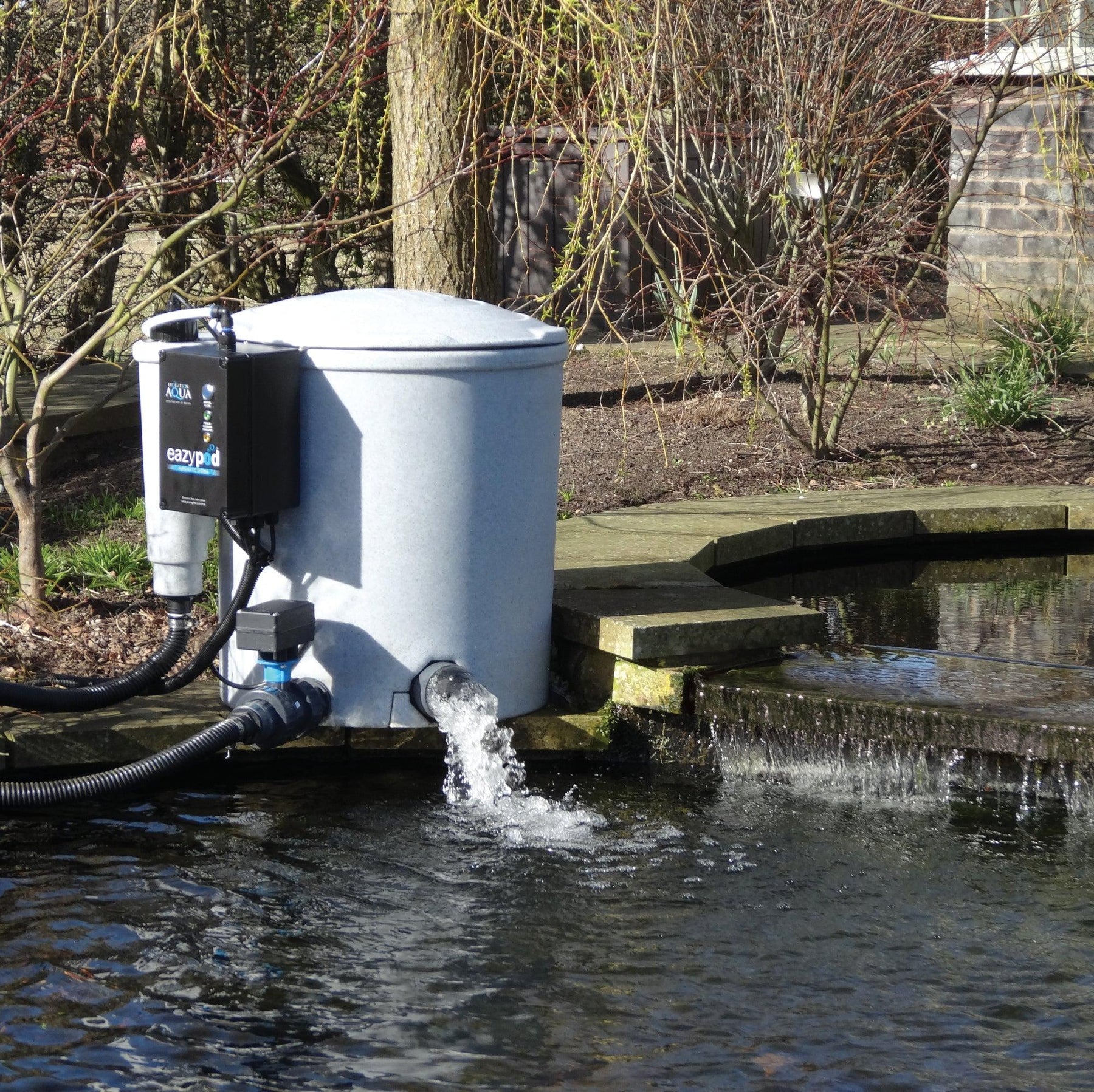 Professional pond filter installation beside an established garden pond